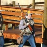 Two hunters walking with rifles.