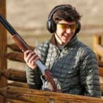 Person holding a rifle outdoors.