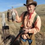 Hunter displaying game in wilderness.