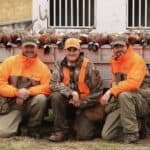 Three hunters in orange gear.